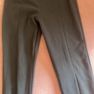 Svarta byxor med dragkedjedetalj - Säljer ett par svarta byxor med en snygg dragkedja längs ena benet. Byxorna har en smal passform och är perfekta för dig som gillar stilrena plagg med en twist. Passar till många olika outfits och är riktigt bekväma.