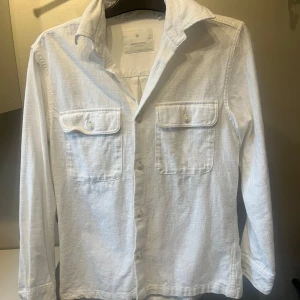 Vit overshirt - Klassisk vit overshirt från Jack and Jones med två bröstfickor och knappar framtill. Knappt använd men säljer för har växt en storlek