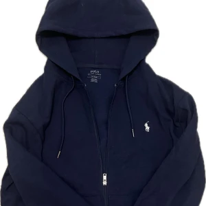 Ralph Lauren Zip | Mörkblå - Säljer en mörkblå, tvär skön Ralph Lauren hoodie, perfekt till sena kyligare kvällar på sommaren. Nästan nyskick, använt max 5-6 gånger, inget smuts eller förstörda ställen, allt som nytt. 