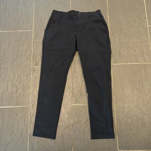 Svarta chinos från Zara - Snygga svarta chinos från Zara i klassisk rak modell. Byxorna har normal passform, diskreta fickor och stängs med knapp och dragkedja. Perfekta för en stilren look och passar till många olika outfits.