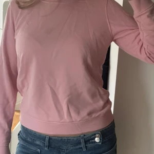 Rosa sweatshirt från GANT i bomull - Säljer en stilren rosa sweatshirt från GANT i mjuk bomull. Tröjan har rund hals, långa ärmar och diskret broderad logga på bröstet. Perfekt för en chill och snygg look. Passar dig som gillar klassisk och enkel stil.