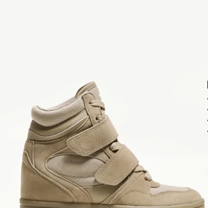 Beige höga sneakers med kardborre - Stilrena höga sneakers i beige mocka och textil med både snörning och breda kardborreband. Skon har en platt sula och rund tå, perfekt för dig som gillar en clean och sportig look.