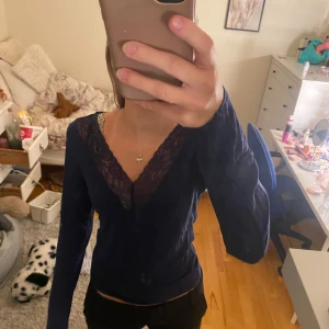 Mörkblå spetströja  från Gina Tricot - Supersnygg mörkblå långärmad blus från Gina Tricot med v-ringning och spetsdetaljer längs halsringningen. Den liknar tröjorna ifrån intimissimi och är bara använd en gång 