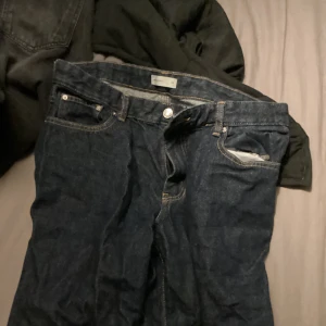 Mörkblå Gina tricot jeans - Säljer ett par klassiska mörkblå jeans med raka ben och fem fickor. Jeansen har en enkel design med kontrastsömmar och metallknapp i midjan. Perfekta för dig som gillar en tidlös look och vill ha ett par jeans som funkar till det mesta.
