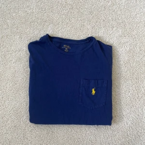 Blå t-shirt från Polo Ralph Lauren - Ralph lauren T-shirt | Skick – 8/10 | Size – S | Hör av dig vid minsta fråga eller fundering! Väldigt litet håll förkommer se sista bild! 