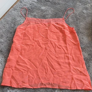 Korallrosa blus Twist & Tango - Snygg korallrosa blus från Twist & Tango med tunna axelband och virkad detalj upptill. Lätt och luftig modell, perfekt för varma dagar. Enkel och stilren design som känns både fräsch och trendig.