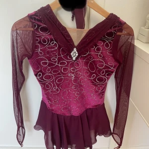 Vinröd glittrig konståkningsklänning med mesh - Säljer en vinröd konståkningsklänning som är så så snygg verkligen!! Nypris är 2499kr, det är märker Jerry. Stl 12-14 år men passar mer Xxs/Xs!