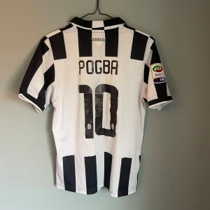 Juventus Pogba #10 fotbollströja Nike M - Vintage Juventus matchtröja med Pogba och nummer 10 på ryggen. Klassisk svartvit randig design, Serie A-patch på ärmen och Jeep-logga på bröstet. Tillverkad i ventilerande Dri-Fit polyester, med krage och snygga detaljer. Säljer på grund av att den inte används 