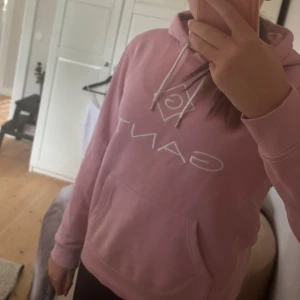 Rosa GANT hoodie xs-s - Säljer en ljusrosa hoodie från GANT med vit broderad logga. Tröjan har huva med snörning, känguruficka och långa ärmar. Mjuk bomullskvalitet och klassisk passform, perfekt för chill dagar. 