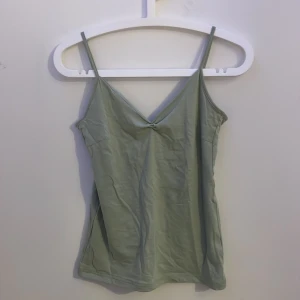 Ljusgrön linnetopp från 157 - Säljer en ljusgrön linnetopp från lager 157 med smala axelband och v-ringning framtill. Toppen är i mjuk bomullsblandning med lite stretch för en bekväm passform. Perfekt att styla med jeans eller kjol för en bekväm look.