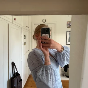 Ljusblå klänning - Superfin ljusblå klänning från Gina Tricot med broderade detaljer och v-ringning. Slutsåld och finns inte längre på hemsidan. Långärmade puffärmar med resår vid handlederna. Helt ny, aldrig använd, som ny kostade den 600kr❣️