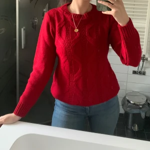 Röd kabelstickad tröja - Snygg röd kabelstickad tröja med rund hals och långa ärmar. Helt oanvänd!