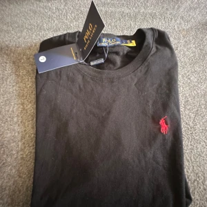 Polo shirt  - Polo Ralph Lauren pikétröjor – helt nya  Säljer två stycken Polo Ralph Lauren pikétröjor i absolut nyskick. 	•	1 st svart 	•	1 st klarblå  Båda är helt nya och oanvända.  Pris: 350 kr styck  Jag bor i Tidaholm, men kan även skicka mot frakt om det önskas.