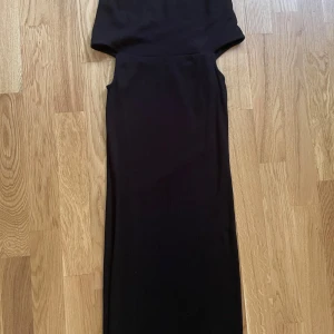 Svart långklänning med ärmlös design - Snygg svart långklänning med ärmlös och figurnära passform. Enkel och stilren design som ger en elegant siluett. Perfekt för dig som gillar minimalistisk stil och vill ha en klänning som funkar till många olika tillfällen.