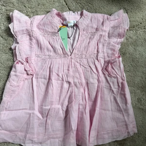 Ljusrosa blus från Gina Tricot - Supersöt ljusrosa blus från Gina Tricot i boho-stil. Toppen har volangdetaljer på ärmarna, v-ringning och fina spetsinslag. . Luftig och flowy passform som ger en chill look🩷