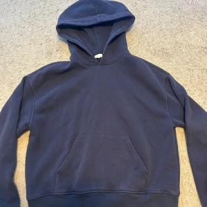 Mörkblå hoodie  - En basic mörkblå hoodie från Gina Tricot med huva och magficka. Tröjan har långa ärmar och ribbade muddar vid ärmslut och nederkant. Den är använd och i bra skick- förutom en liten fläck på fickan ( visas på sista bilden) .