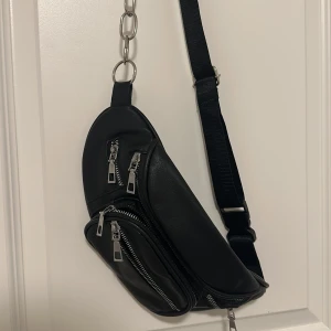 Svart axelväska med kedjedetalj -  svart axelväska med silvriga dragkedjor 