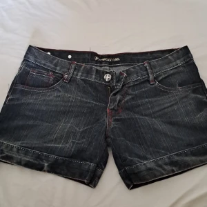 Low waist jeans shorts yk2 style - Jättefina jeans shorts som är low waist men lite längre. Yk2 style med rock i ena bakfickan. Mörkblå och svart med röda detaljer. Köpt från en marknad i Thailand. Det står XL på dem men jag tycker inte att pass formen stämmer till det. 