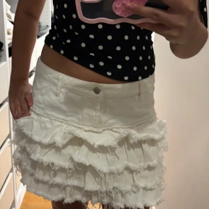 Vit volangkjol i jeans – Monki, L (passar M) -  Supersöt vit jeanskjol från Monki i storlek L, men sitter mer som M. Mjukt jeanstyg med flera lager volanger och råa kanter för en trendig men söt look. Perfekt för sommaren, festivaler eller första skoldagen. Använd få gånger, mycket fint skick.  📏 Storlek: L (M-passform) 🎨 Färg: Vit 🏷️ Märke: Monki 