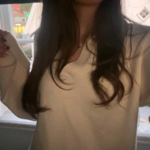 Beige stickad v-ringad tröja - Supermysig beige stickad tröja från Gina med v-ringad hals och bred ribbad kant nedtill och vid ärmslut. Perfekt att slänga på sig när det är lite kyligt ute. Snygg och enkel design som funkar till allt. Långärmad och loose fit.