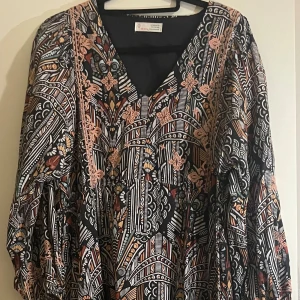 Mönstrad långklänning Odd Molly - Säljer en sjukt snygg långklänning från Odd Molly med unikt grafiskt mönster i svart, vitt, orange och beige. Klänningen har v-ringning, långa puffärmar och broderade detaljer. Perfekt för dig som gillar boho vibes och coola prints.