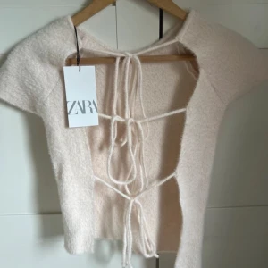 Stickad topp med snörning från Zara - Superfin beige croppad topp från Zara med korta ärmar och öppen rygg med snygg snörning. 