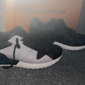 Louis Vuitton monogram sneakers - Säljer ett par Louis Vuitton sneakers med ikoniskt monogrammönster i brunt och svart, kombinerat med vita paneler. Skorna har snörning, rund tå och en platt, vit sula med LV-logga undertill. Tillverkade i skinn med lyxig känsla och detaljerad finish. Box, dustbag och extra skosnören ingår.