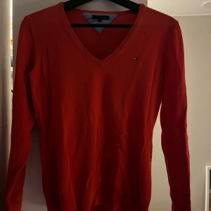 Röd stickad v-ringad tröja  - Säljer denna tröjan från Tommy Hilfiger! Storlek M, säljer direkt för 200kr. 