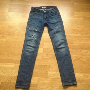 Acne Studios blå skinny jeans 29/32 - Snygga blå jeans från Acne Studios i modellen Ace/Stretch Vintage. Skinny fit med slitna detaljer och klassisk femficksdesign. Tillverkade i 98% bomull och 2% elastan för skön stretch. Perfekt för dig som gillar en smal siluett och coola slitningar.