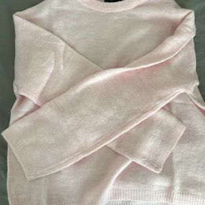 Ljusrosa stickad tröja - Mysig ljusrosa stickad tröja med rund hals och långa ärmar. Den är använd 4-5 gånger men ser inte jätte använd ut. Finns även att köpa i vit. Om man vill ha båda så får man självklart bättre pris 