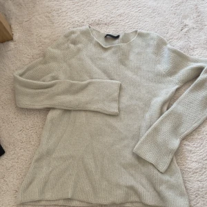 Beige stickad tröja från FFC - Säljer en beige stickad tröja från FFC i storlek S. Tröjan har en enkel, rund hals och är långärmad. Materialet är en lyxig mix av 70% ull och 30% kashmir, vilket gör den supermjuk och skön. Perfekt för dig som gillar stilrena och mysiga plagg.