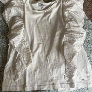 Vit blus med volangärmar från Happy Republic - Supersöt vit blus från Happy Republic med breda volangärmar i broderad bomull. Ärmarna har fina hålmönster och ger en extra touch till looken. Hör av dig vid frågor!💕