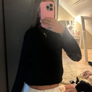 Svart stickad polotröja - Säljer en svart stickad polotröja med grov struktur. Tröjan har lång ärm och en hög krage som ger en chill och stilren vibe. Perfekt att matcha med jeans eller kjol för en enkel men snygg look. Materialet är mjukt och värmande, passar dig som gillar klassiska färger.