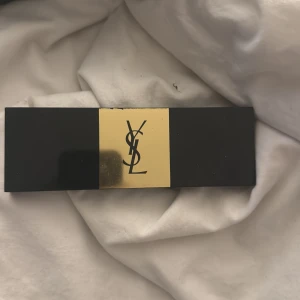 YSL Couture Variation ögonskuggspalett - Snygg ögonskuggspalett från YSL med 10 nyanser i nude och bruna toner, både matta och skimrande. Svart och guld förpackning med spegel inuti, perfekt för att skapa allt från naturliga till mer intensiva looks. Paletten är elegant och stilren, med YSL-logga på locket.