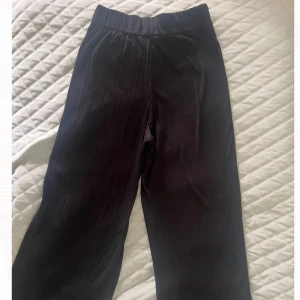 Svarta ribbade wide byxor från Monki - Svarta ribbade byxor från Monki i storlek XS. De har en bred och relaxed passform med hög midja och är tillverkade av mjukt material med polyester, viskos och elastan. Midjebandet är stretchigt 💗 Perfekta att ha hemma❤️ Innerbenslängd: 65 cm 