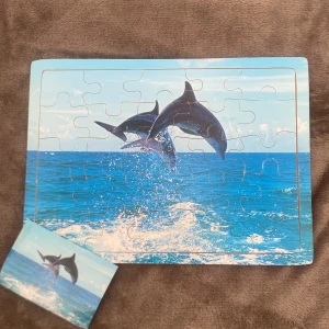 Djurpussel: Delfiner & Lejon - Två färgstarka pussel med djurmotiv – ett med hoppande delfiner i havet och ett med ett majestätiskt lejon vid solnedgången. Perfekt för dig som gillar djur och vill ha en rolig och avslappnande aktivitet!