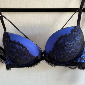 Blå bh med svart spets från New Yorker - Snygg super push up blå bh från New Yorker med svart spets och cool snörningsdetalj på sidorna. Endast testad.