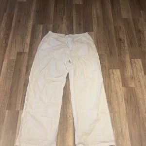 Vita linnebyxor från Gina Tricot - Snygga vita linnebyxor från Gina Tricot i storlek S. Byxorna har en relaxed passform med rak och wide ben, elastisk midja med snörning och är tillverkade i mjukt linne. Perfekta för chill dagar och sommarhäng. Enkla att matcha med crop tops eller hoodies.