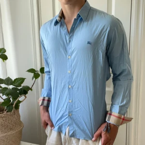 Burberry blå skjorta - Riktigt fet Burberry skjorta! Inga större defekter förutom fett fläckar under ärmarna som inte märks när man använder den. Modellen bär M och är 180,75 kg. Hade sagt att det är ungefär den optimala fiten. Kom med frågor! 🙏