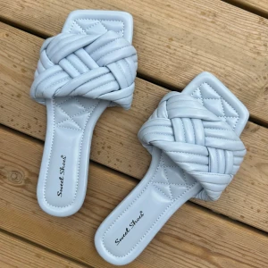 Ljusblå sandaler från Sweet Shoes - Säljer ett par ljusblå sandaler från Sweet Shoes med flätad ovandel och quiltad sula. De har fyrkantig tå och är tillverkade i syntetmaterial som ger en mjuk och skön känsla. Perfekta för dig som gillar trendiga detaljer och vill sticka ut med en cool färg.