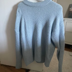 Ljusblå stickad tröja  - Mysig ljusblå stickad tröja med rundad hals och långa ärmar. Tröjan har en relaxed passform och ribbad kant vid halsen. Perfekt för att hålla sig varm och ändå se chill ut. Passar dig som gillar enkel och stilren design.