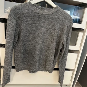 Grå stickad tröja från MNG - Säljer en enkel och snygg grå stickad tröja från MNG. Tröjan har rund hals, långa ärmar och ribbade muddar vid hals, ärmslut och nederkant. Perfekt för lager-på-lager och chill dagar. Passar dig som gillar basic och stilrent. Använd fåtal gånger, sticks ej mot huden.