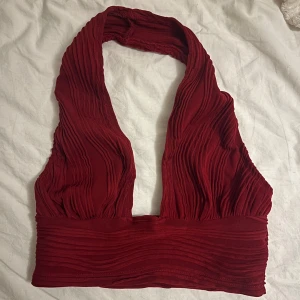 Röd halterneck topp - Snygg röd halterneck topp med veckad design. Perfekt för en kväll ute eller en speciell tillställning. 