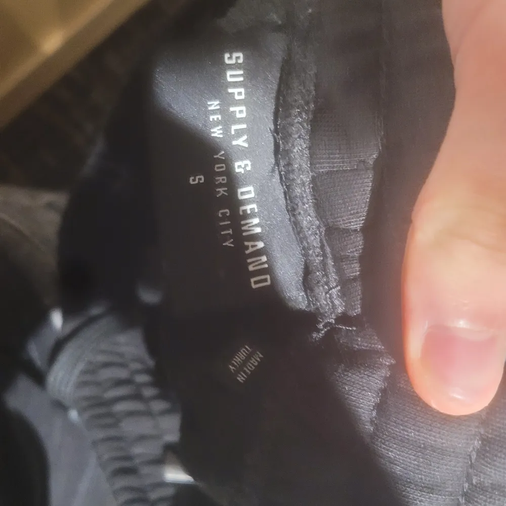 Svarta byxor från Supply & Demand med tryck på benen. De har en avslappnad passform och är perfekta för en casual look. Byxorna har elastisk midja för extra komfort.. Farkut & Housut.
