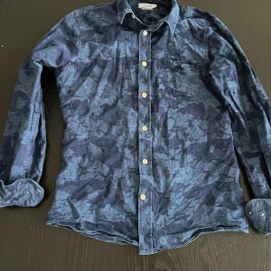 Blå camouflagemönstrad skjorta från J.Lindeberg - Snygg blå camouflagemönstrad skjorta från J.Lindeberg i slim fit. 