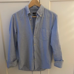 Ljusblå skjorta från Alcott & Co. - Snygg ljusblå skjorta från Alcott & Co. i 100% bomull. Skjortan har en klassisk design med knappar framtill och en bröstficka. Perfekt för en stilren look.