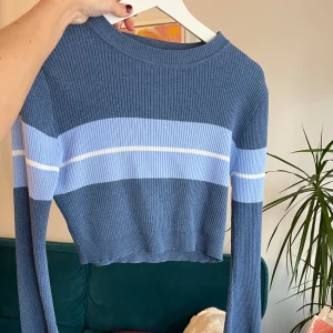Blå ribbad croppad tröja - Säljer en snygg blå ribbad tröja med vita och ljusblå ränder. Tröjan är croppad och har långa ärmar, perfekt för en trendig look. Passar bra till både jeans och kjol. Hör av dig vid intresse! 💙xs-s/tight m