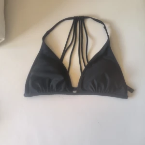 Svart bikiniöverdel med snörning - Snygg svart bikiniöverdel med flera smala band som går ihop i nacken för en unik look. Perfekt för stranden eller poolen. Enkel och stilren design som passar till det mesta.