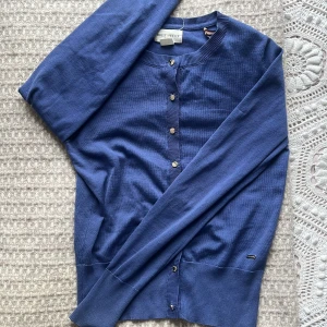 Blå kofta från Gant - Säljer en stilren blå kofta från holly & whyte. Den har långa ärmar och knappar framtill. Perfekt för lager-på-lager under kyligare dagar.  Storlek XS men passar även S 💞