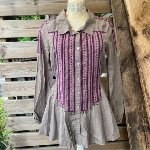 Odd Molly grå skjorta med vackra detaljer  - Jätte fin skjorta från Odd Molly i stl 1, motsvarar stl S, jag skulle säga stl 36z Unik grå skjorta med lila broderi och dekorativa metallbrickor. Skjortan har långa ärmar och knappar framtill. På baksidan finns ett broderat citat. Perfekt för dig som vill sticka ut! Det finns en mycket svag färgskiftning under ärmarna, detta syns enbart om man granskar mycket noga, går inte att fånga på bild, men jag vill nämna det då jag själv är en petig köpare.